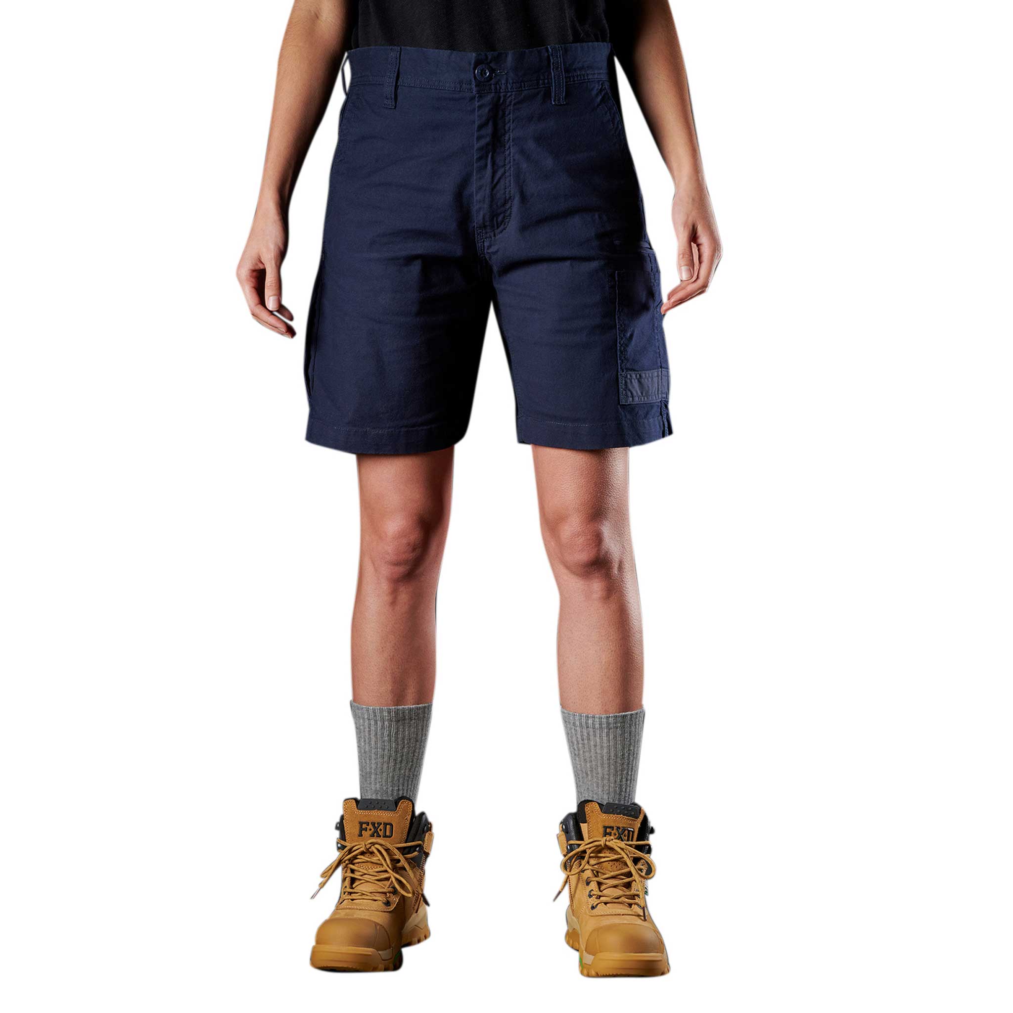 A person standing against a white background, wearing navy blue work shorts and beige work boots.