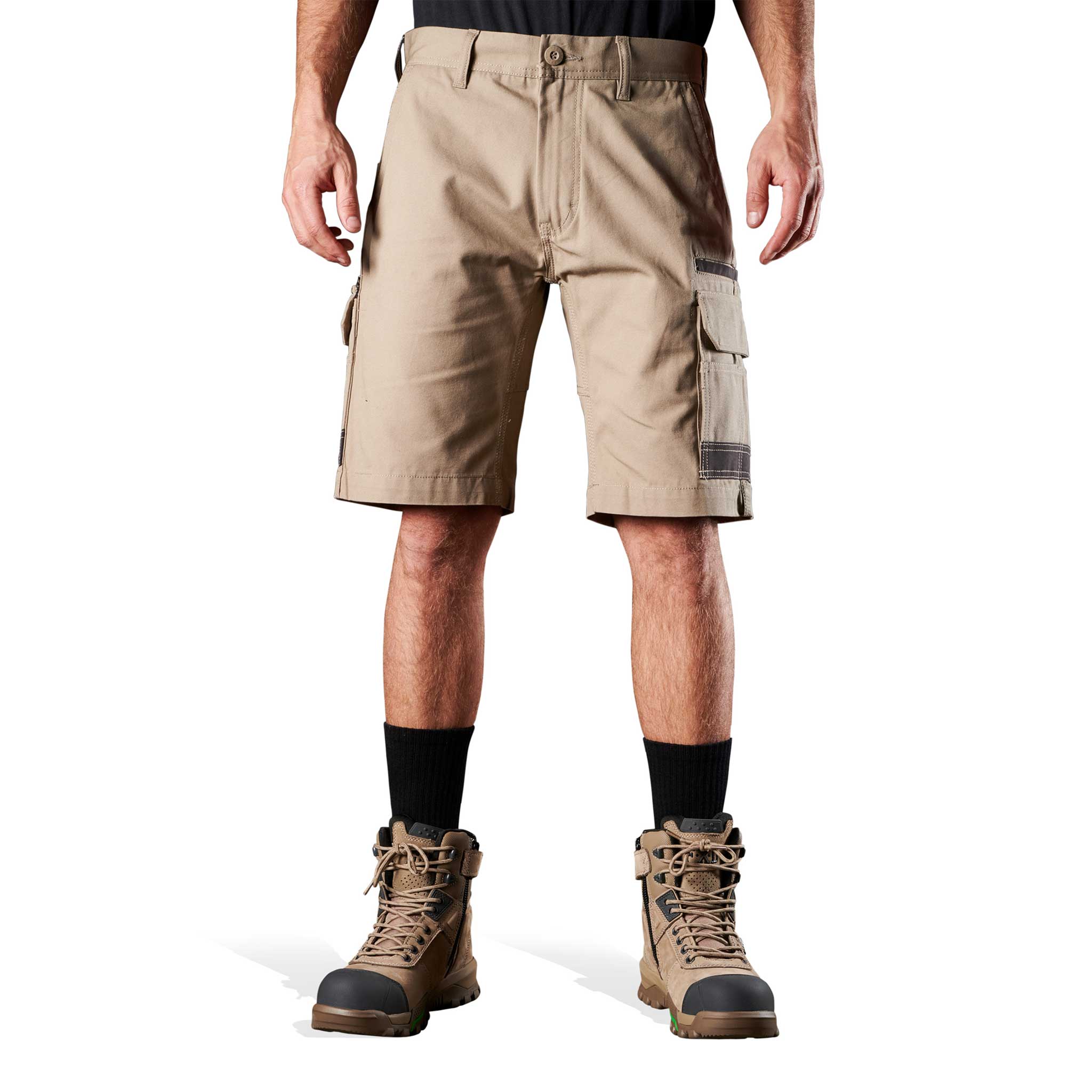 A person standing against a white background, wearing beige work shorts and brown boots.