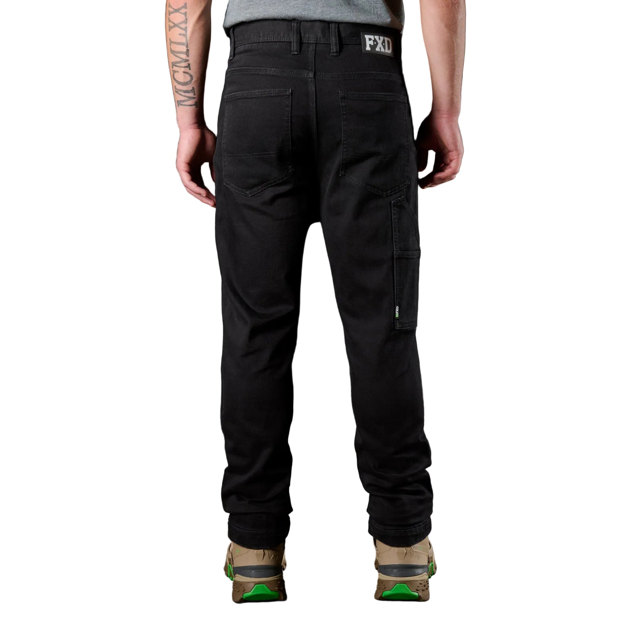 Person wearing black pants with FXD branding on a dark background