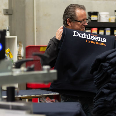 Man customizing navy blue fabric in Dahlsens For the Builder logo print workwear